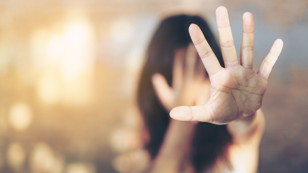 Woman shielding her face, illustrating a sign of an abusive relationship