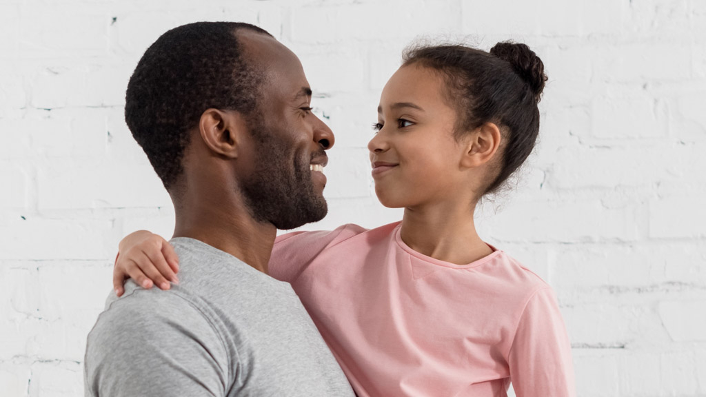Handsome young father holding his daughter at kitchen